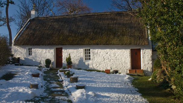 Whitewashed thatched cottage in snow