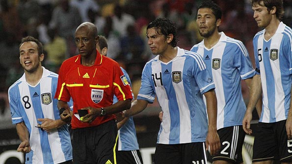 Referee Ibrahim Chaibou, in the red top, is surrounded by Argentina players after he awarded a penalty against them in the 4-1 defeat by Nigeria, in Abuja.