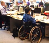 Workplace with man in a wheelchair working at a desk next to an able-bodied colleague