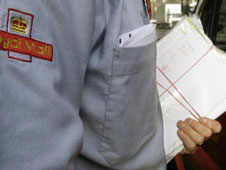 Postie with bundle of letters secured by red rubber bands