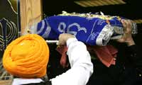 The Sikh holy book, wrapped in embroidered cloth, is carried through the temple door