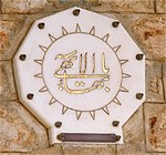 Bahai symbol on a wall: calligraphy surrounded by a picture of a sun