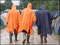 Three people walking through Glastonbury's mud