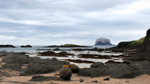 Sand and rocks ar North Berwick beach, with the Bass Rock in the background