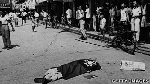 香港九龙某徙置区内一名暴动死者被盖上青天白日满地红旗（10/1956）