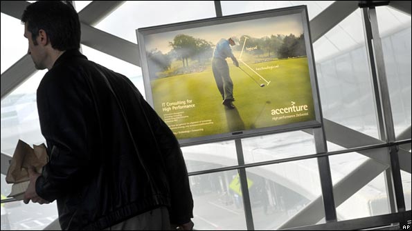 A passenger walks past an Accenture advertisement featuring Tiger Woods at San Francisco International Airport
