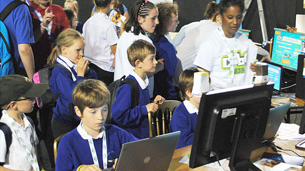 In a room fill of schoolchildren, two boys tap away at laptops.