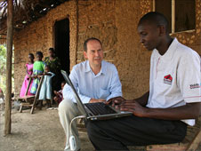 Rory Cellan-Jones and Martin Rogena outside a hut with a laptop computer