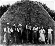 Workers gather around a haystack