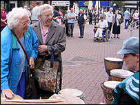 Young person shows older folk how to drum