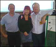 Three people standing near a heater.