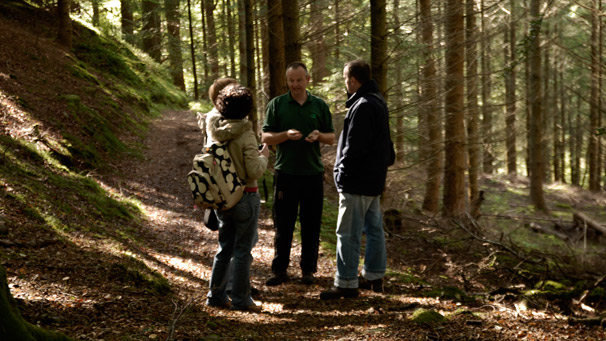 A ranger talks to a group of people in a forest