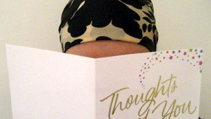 Lisa, wearing a headscarf, is partially obscured as she reads one of the many Get Well Soon cards she received