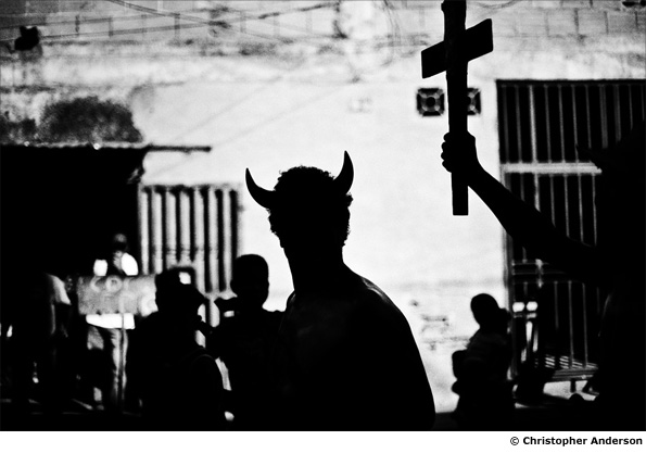 A man in a devil costume runs around the streets of La Vega before a rally for Chavez