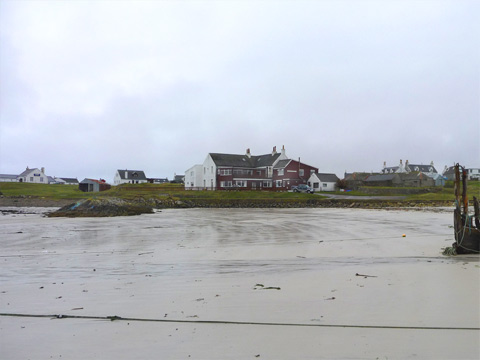 Colour view of Scarinish from the beach on a overcast day. The remains of a wrecked ship can just be seen to the right of frame.