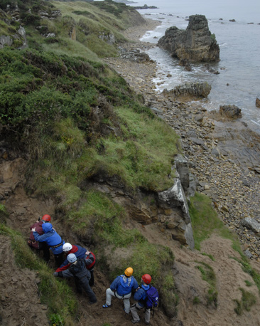 A group of participants climb up a steep, sandy slope.