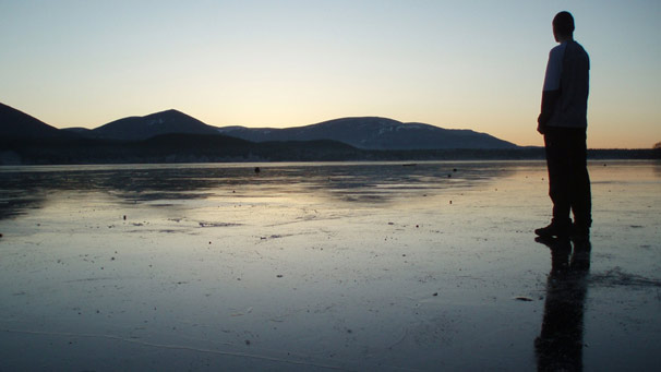 Man standing on ice as sun sets