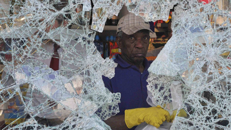 A man clears up after the looting of a supermarket in London (Reuters)