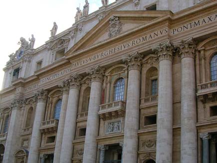 Facade of Saint Peter's Basilica, framed by pillars with Latin legend over the doors