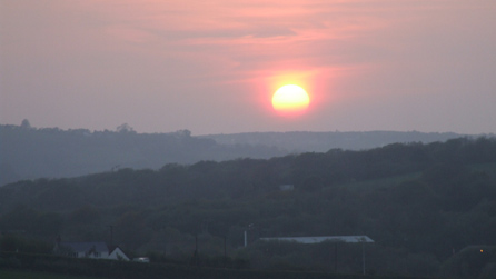 yr haul yn machlud fel pelen o dân uwch Dyffryn Aman