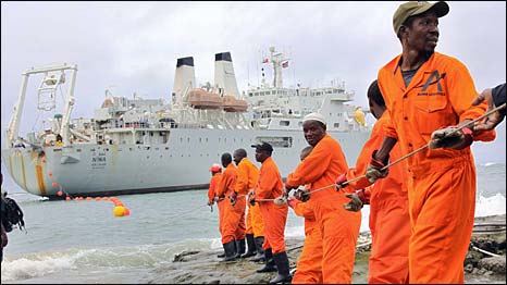Workers pull part of the fibre optic cable to land