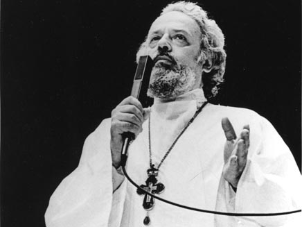 Father Alexander Men, middle-aged, in the outfit of a Russian Orthodox priest and speaking passionately into a microphone