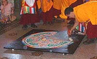  A monk has brushed away a quarter of the mandala into heaps of grey sand