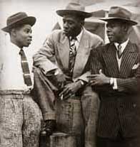John Hazel, Harold Wilmot and John Richards aboard the Windrush, Tilbury 1948. The men are dressed in suits and hats.