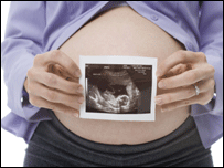 woman's pregnant tummy with scan photo