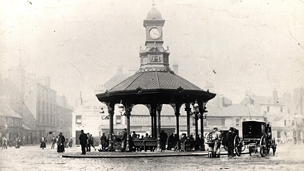Black and white view of the Bridgeton Cross Shelter, an octagonal shelter supported on slim columns with a short clock tower above.