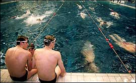 Two swimmers sat beside a pool