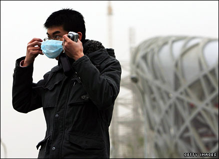 A tourist puts on a smog mask in front of Beijing's National Stadium